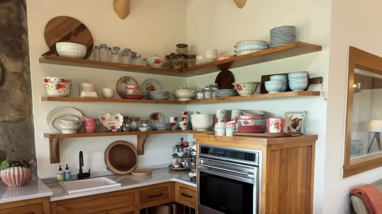 Bowls, cups, and other dishes arranged on open shelves in kitchen