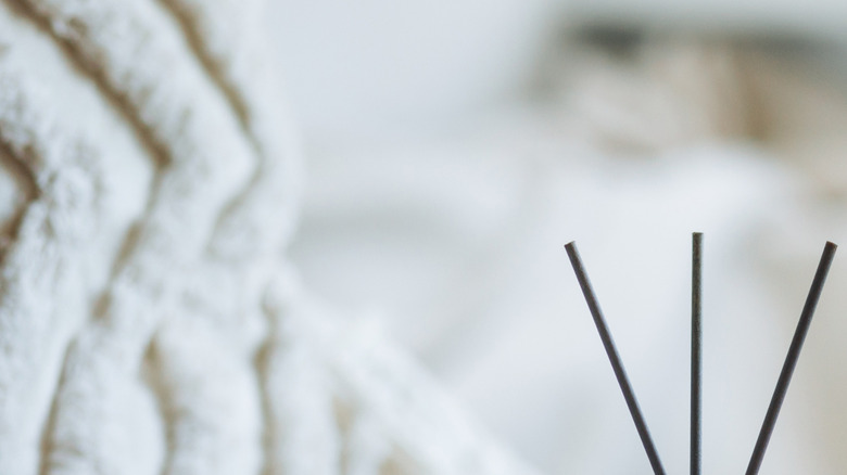 White candles, flowers, and a reed diffuser sit on a wooden tray.