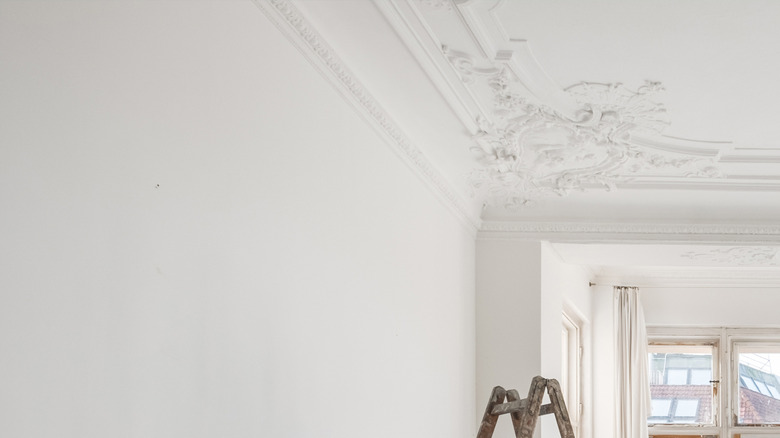 A split shot of a room: walls, ceiling, and trim are painted white on the left and green on the right.