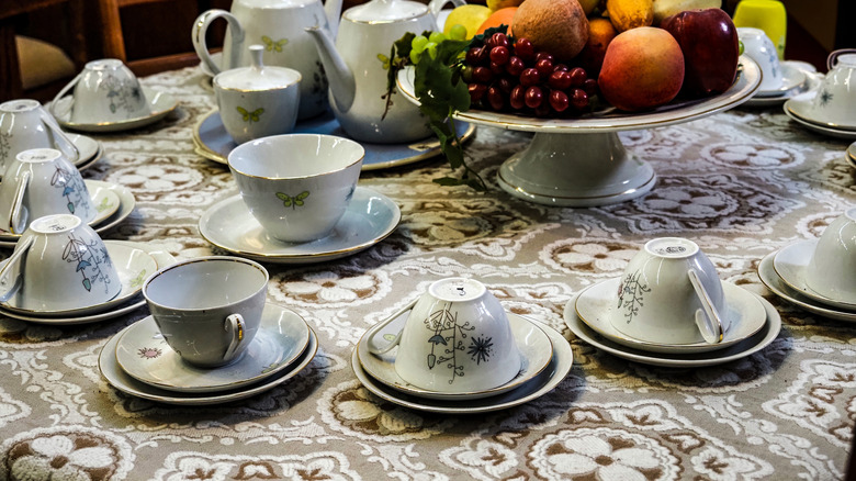 A vintage set of teacups and saucers on a tablecloth