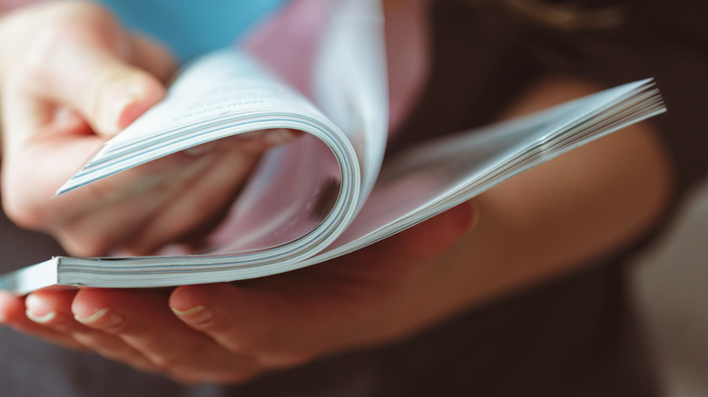 Close up of hands flipping through magazine.