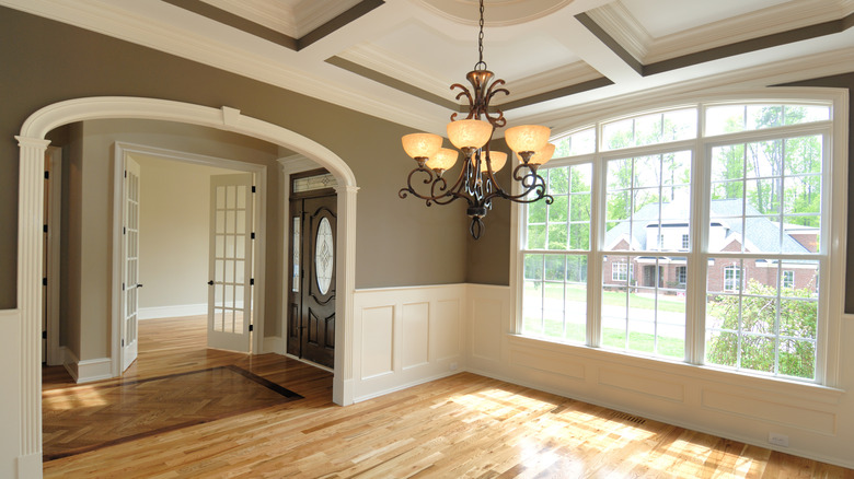 A modern dining area with green walls and traditional white trim