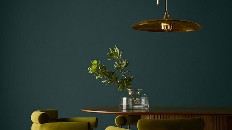 A small eating space with Hidden Gem as the background with green chairs and metallic table and lights