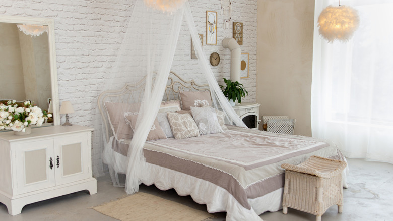 A white bedroom with a canopy-style bed, vintage furniture, and soft decor