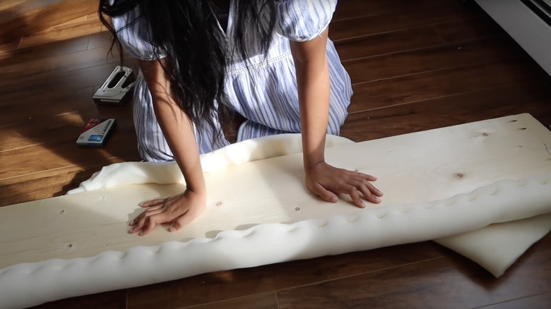 A person upholstering bed frame with foam DIY