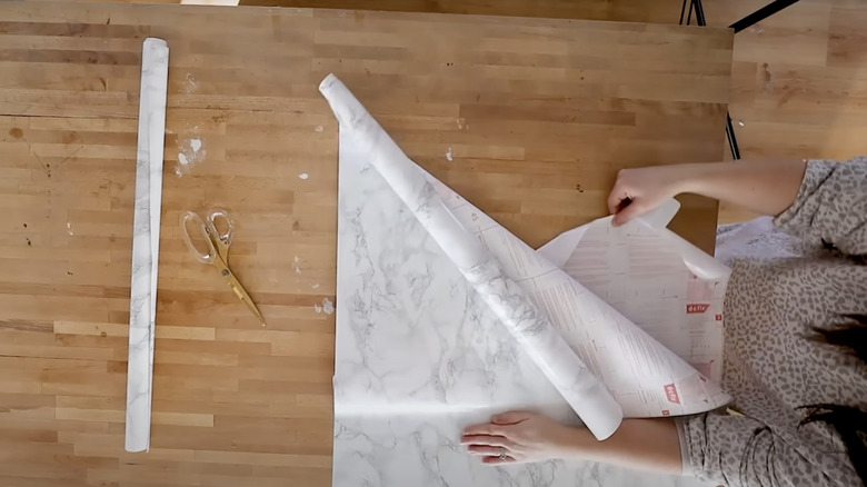 A person applying marble contact paper to a countertop