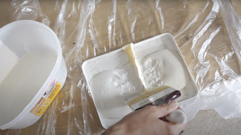 A brush dipped in two colors of paint for DIY limewash