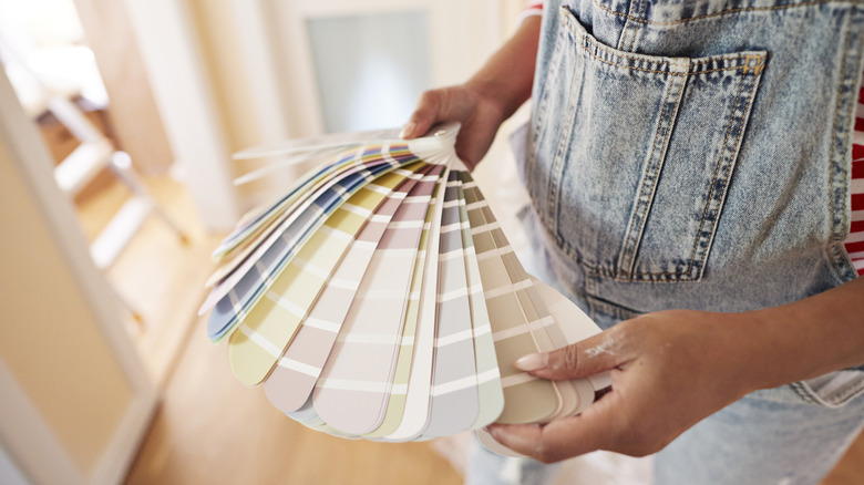 Person wearing overalls looking at neutral paint swatches