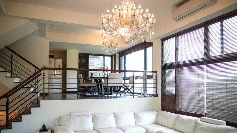 Chandelier over white leather sectional in modern living room