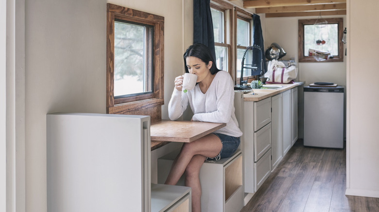 Young woman in a tiny home enjoying a cup of tea.