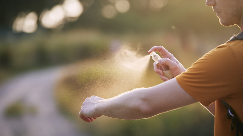 Man spraying arm with repellant