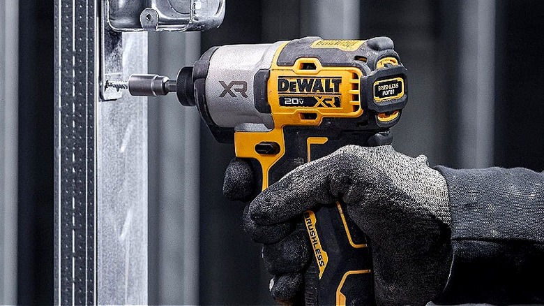 A gloved hand using a DeWalt power tool