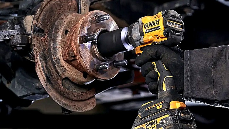 Close-up of a person using a DeWalt impact wrench on car wheel repair