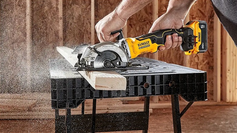 A person using a DeWalt saw to cut through lumber