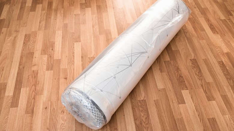 A vacuum-sealed mattress laying on a wood floor.