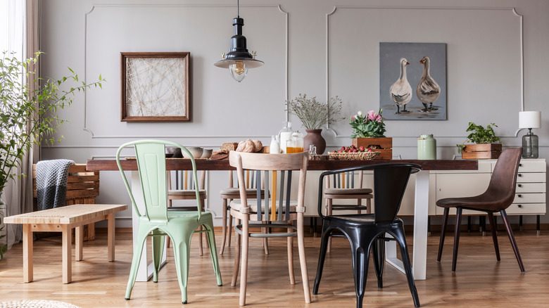 Eclectic dining room with a wood table, pendant lighting, and an assortment of chairs.