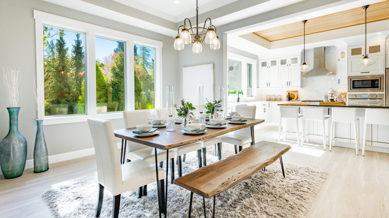 Farmhouse dining room with a wood table and bench and white upholstered chairs.