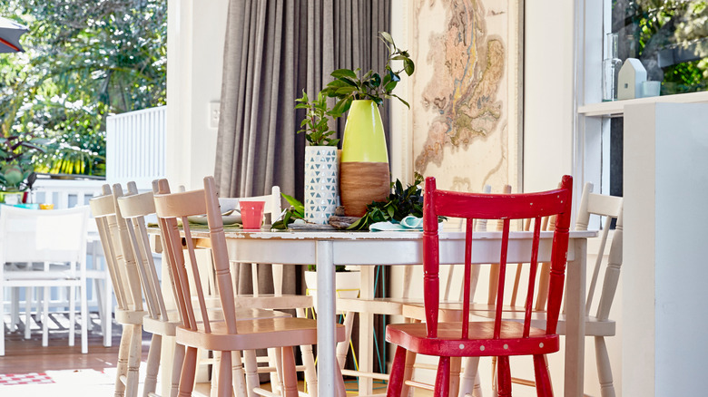 Shaby chic dining room with a white, wood table, wood chairs with a red head chair, and a map on the wall.