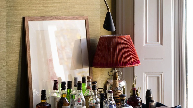 Home bar table in in front of wall with grasscloth wall paper.