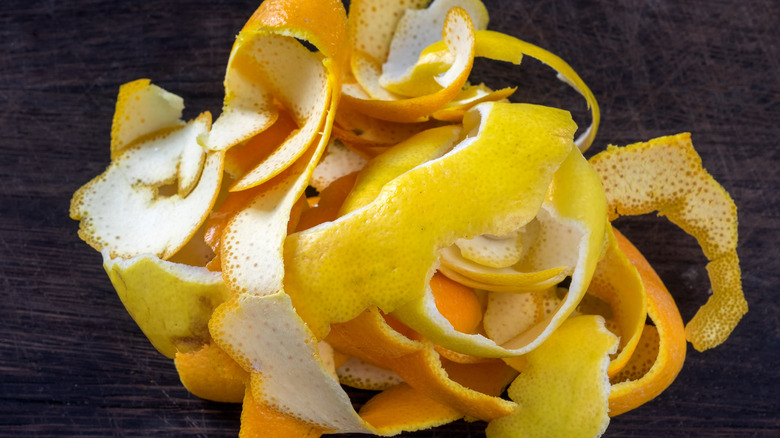 A pile of fresh citrus peels on a cutting board