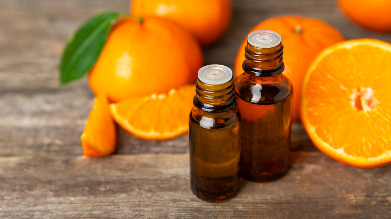 Bottles of citrus oil sitting next to tangerines on a table