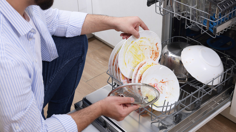 Man loading dirty dishes into dishwasher