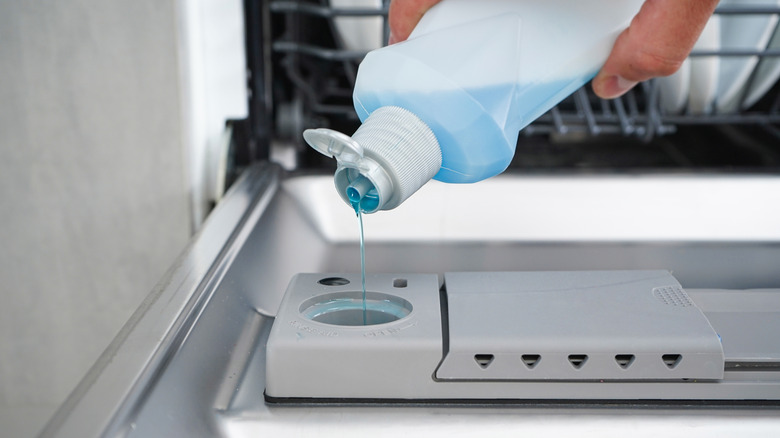 Person pouring rinse aid into dish washer