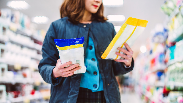 woman in store looking at two different bags of cleaning wipes