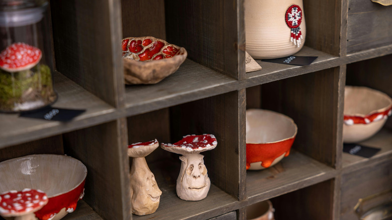 Mushroom-themed pottery in red and cream colors is displayed in a wooden cabinet
