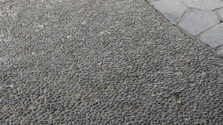 Close-up of a durable exposed aggregate driveway with a natural stone border