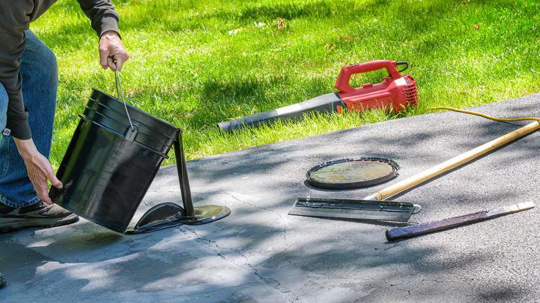 Person pouring new asphalt to fix cracks in an asphalt driveway