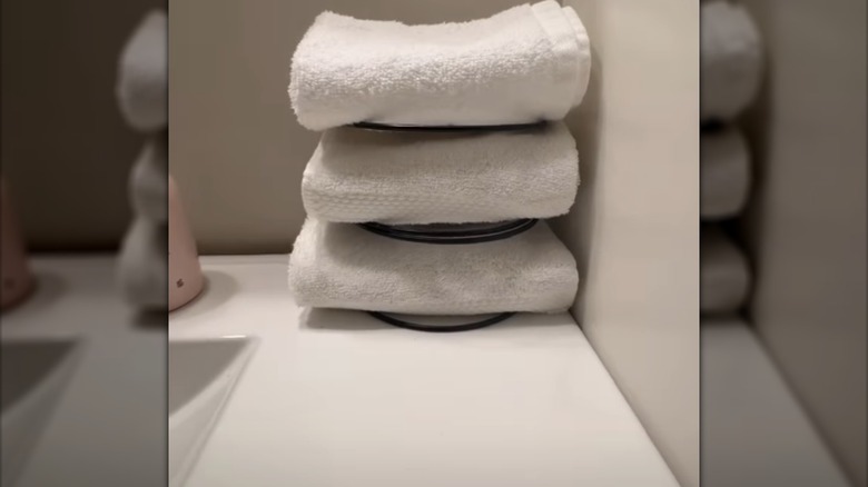 DIY small bathroom towel storage solution made from napkin holders sits on the edge of a bath tub.