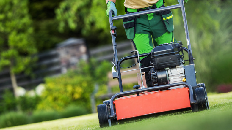 A man using a gas-powered aerator on a lawn