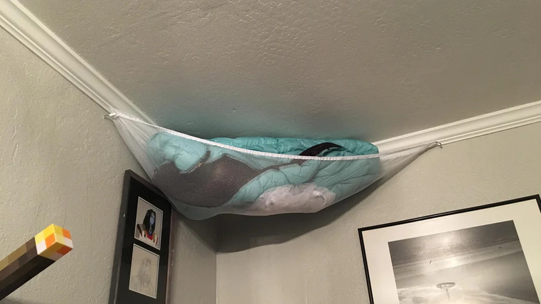 Hanging hammock filled with blankets in a bedroom corner by the ceiling
