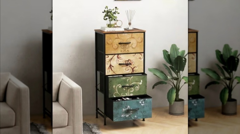 A vertical four-drawer fabric dresser with yellow beige, green, and blue floral-patterned drawers.