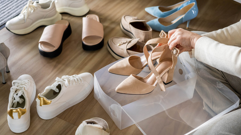 A person organizes a shoe collection on their floor