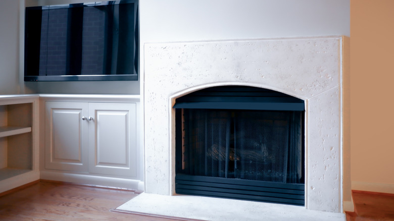 Plain white fireplace with black metal screen in living room