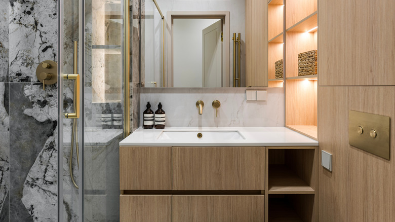 A small bathroom with wooden cabinets and gold fixtures.