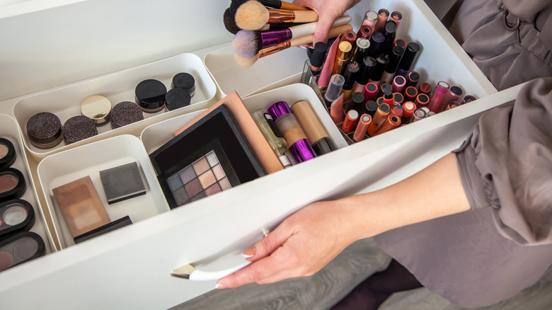 Woman putting makeup brushes away in a drawer