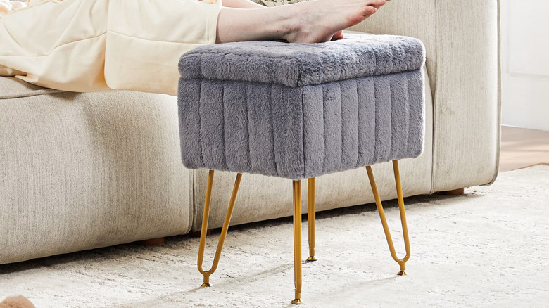 Person putting their feet on a gray fuzzy storage stool ottoman