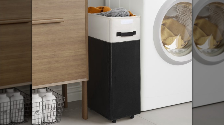 Tall narrow laundry hamper next to a washing machine