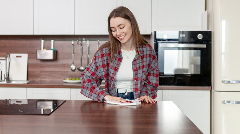 woman using paper towel to clean empty kitchen counter