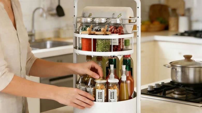 hands reaching for jars on rotating spice rack towel holder