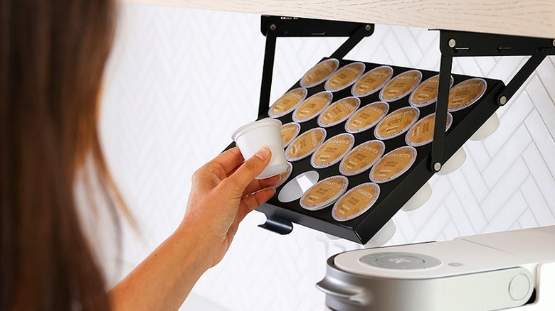 Person grabbing a single-serve coffee pod from an under-counter holder