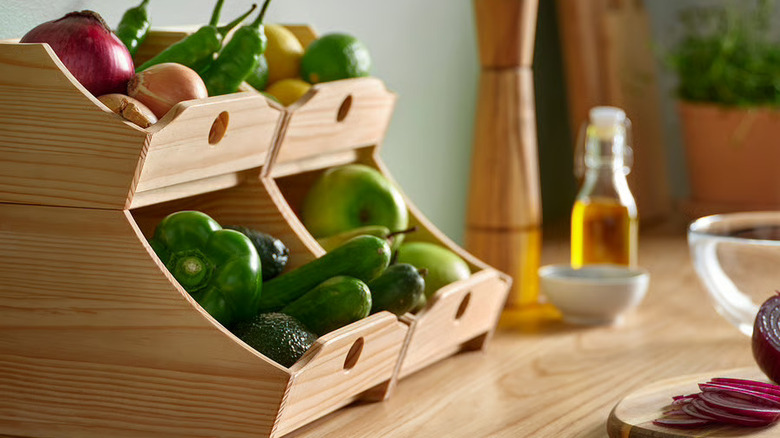 Two sets of wood-toned IKEA food storage boxes filled with produce sit on top of a butcher-block countertop.