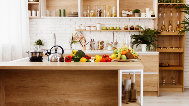Kitchen counter cluttered with fruits and vegetables.