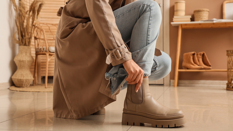 Person putting on boots in styled entryway