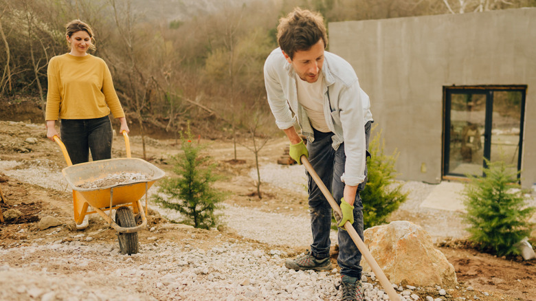 Two people doing landscaping work with rocks outside of a new home