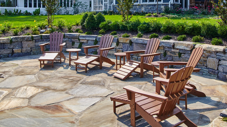 Five brown Adirondack chairs in a sunken flagstone patio area