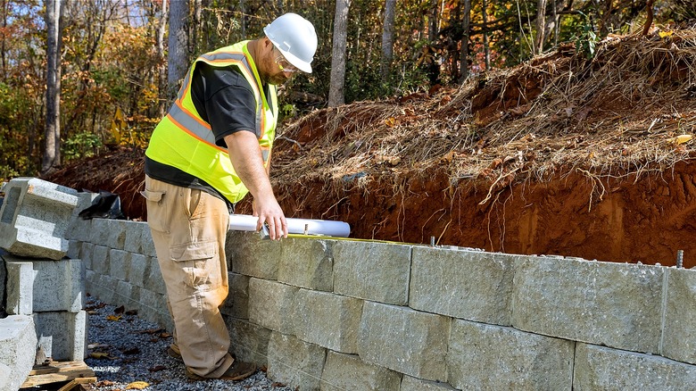 A professional in construction gear works on a concrete block retaining wall.